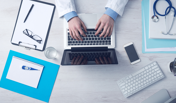 a person sitting at a desk with a laptop and a keyboard